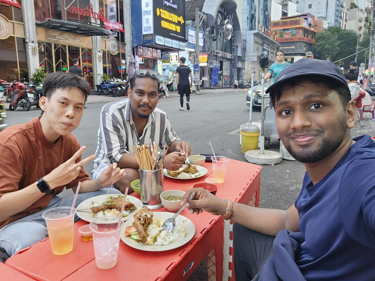 three men sitting at a table with food on it